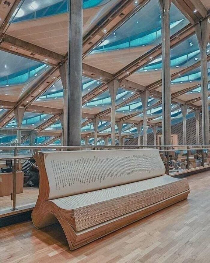 Panca a forma di libro aperto all'interno di una biblioteca moderna e grandiosa con architettura in vetro e metallo da tutto il mondo. Panca a forma di libro aperto all'interno di una biblioteca moderna e grandiosa con architettura in vetro e metallo da tutto il mondo.